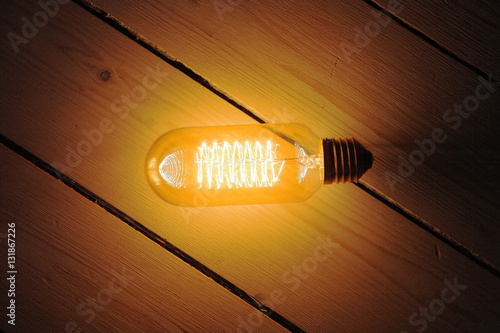 edison bulb glowing on rustic wood floorboards Fototapet