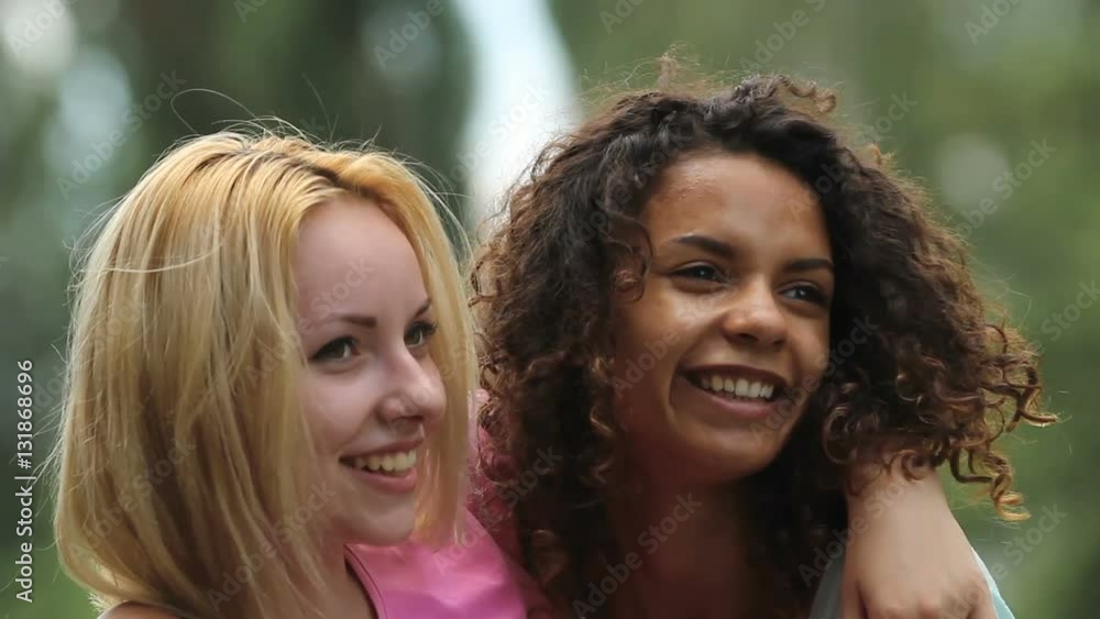 Gay female couple smiling, embracing tightly while posing in front of camera Gay female couple smiling, embracing tightly while posing in front of camera