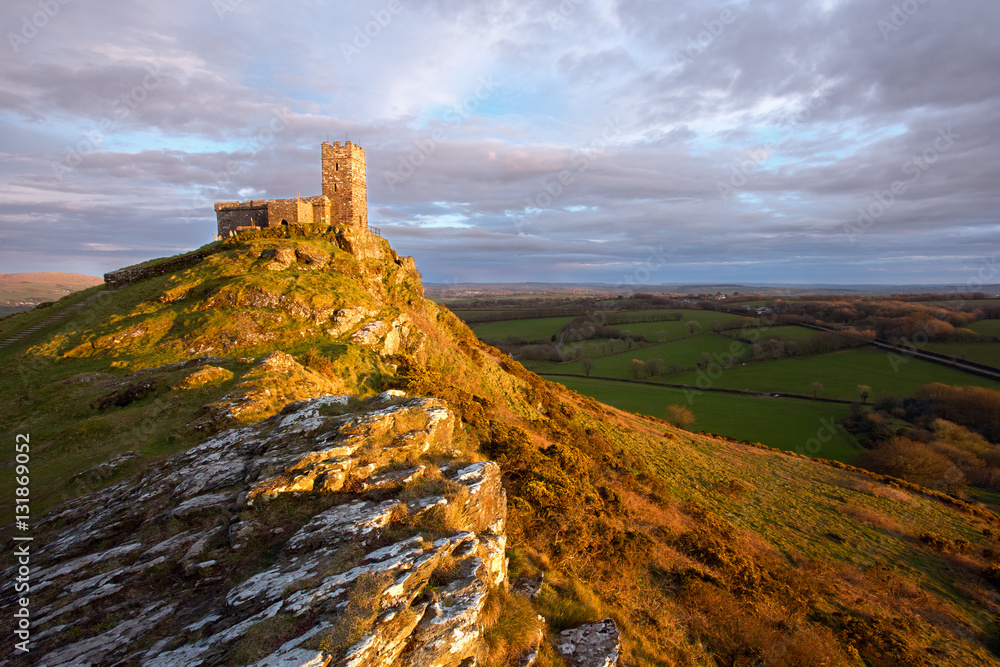 The church at Brentor Devon Uk bathed in rich golden sunlight at sunset.