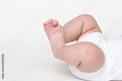 Legs and feet of a happy baby on white background