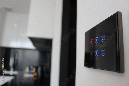 Electronic touch screen light and temperature control panel wall mounted in a modern apartment room. photo