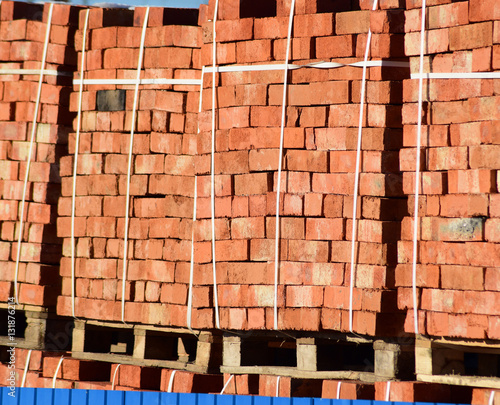 Red bricks stacked into cubes. Warehouse bricks. Storage brickworks products