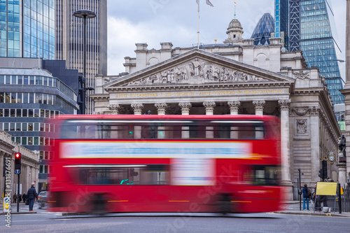 London, England - Iconic red double decker bus on the move with the Royal Exchange building at background © zgphotography