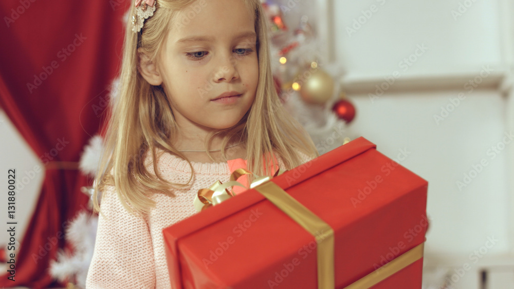 Blue-eyed little blonde girl is delighted from her New Year's gift