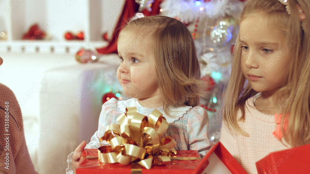 Fototapeta premium Happy family with two young daughters at the Christmas tree with gifts