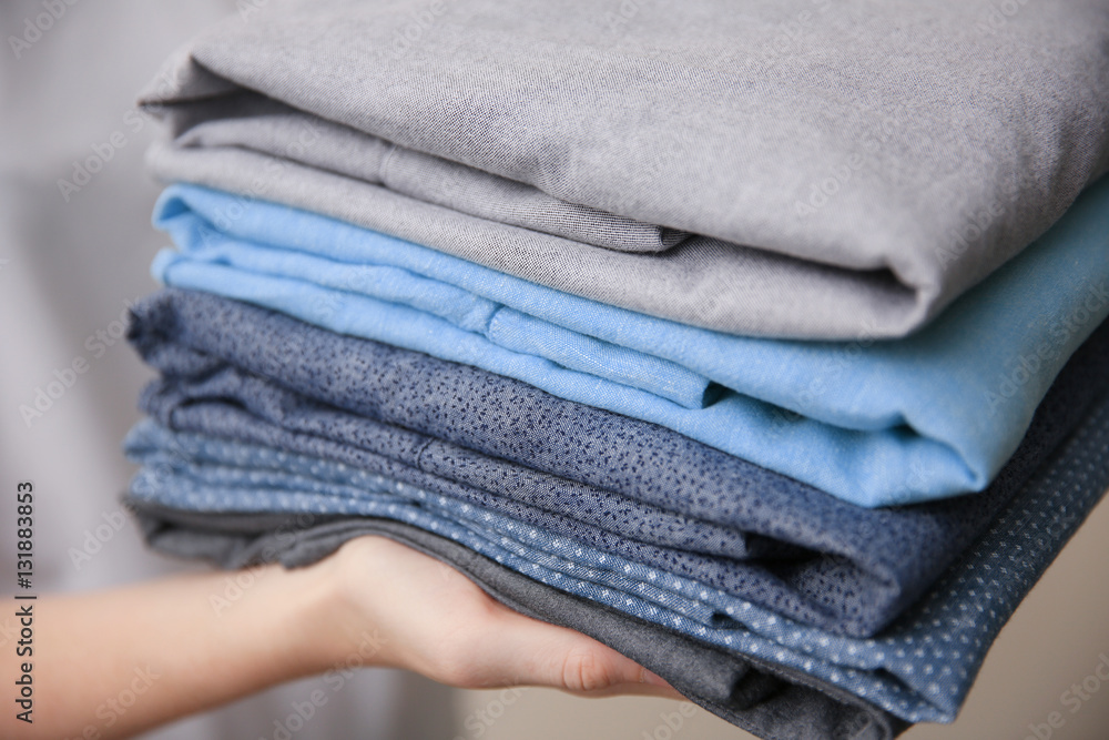 Woman holding folded clothes in hands, closeup Woman holding folded clothes in hands, closeup