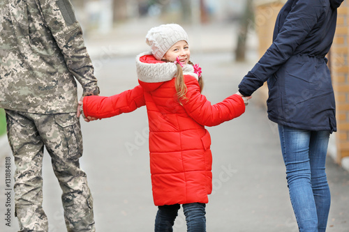 Little girl walking outdoors with mother and military father