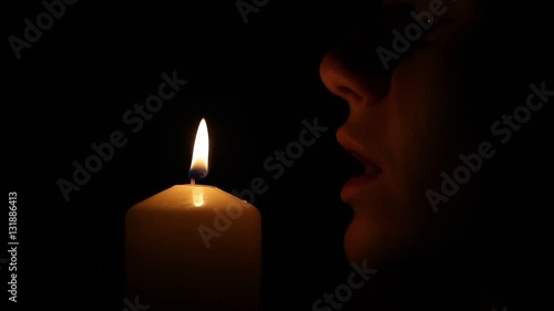 Woman blows out the candle in the dark

