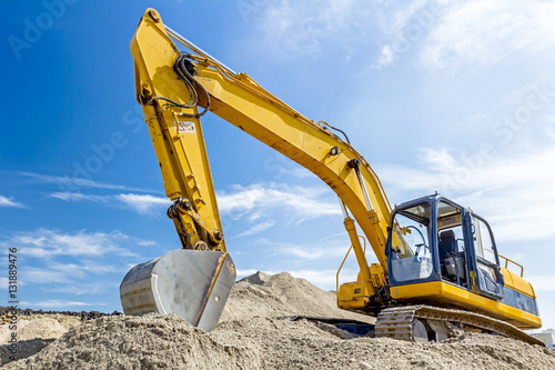 Tableau sur toile Excavator is preparing pile of sand for loading in truck on buil