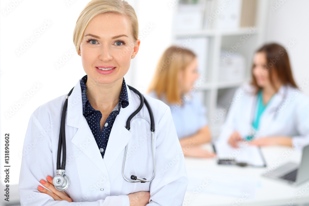 Female doctor smiling on the background with patient and his physician in hospital Female doctor smiling on the background with patient and his physician in hospital