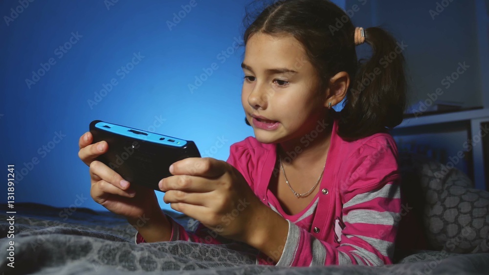 teen kid girl playing portable video online game a console kid at night indoors