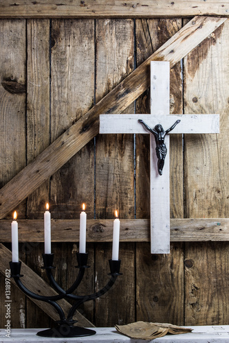 Wooden white cross, prayer and candles on a background of the old wooden walls
