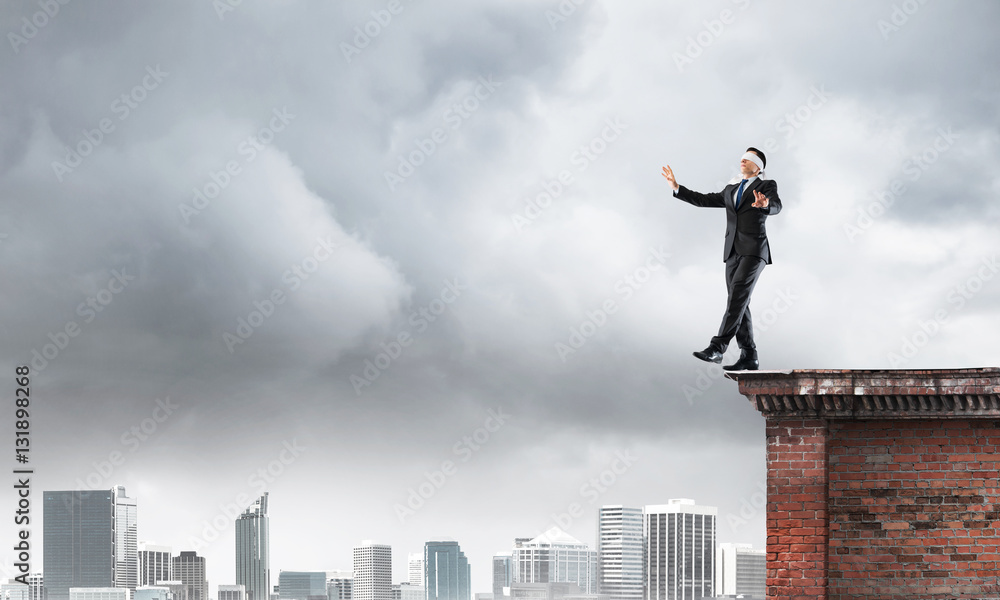 Danger and risk concept with businessman making step from edge Danger and risk concept with businessman making step from edge