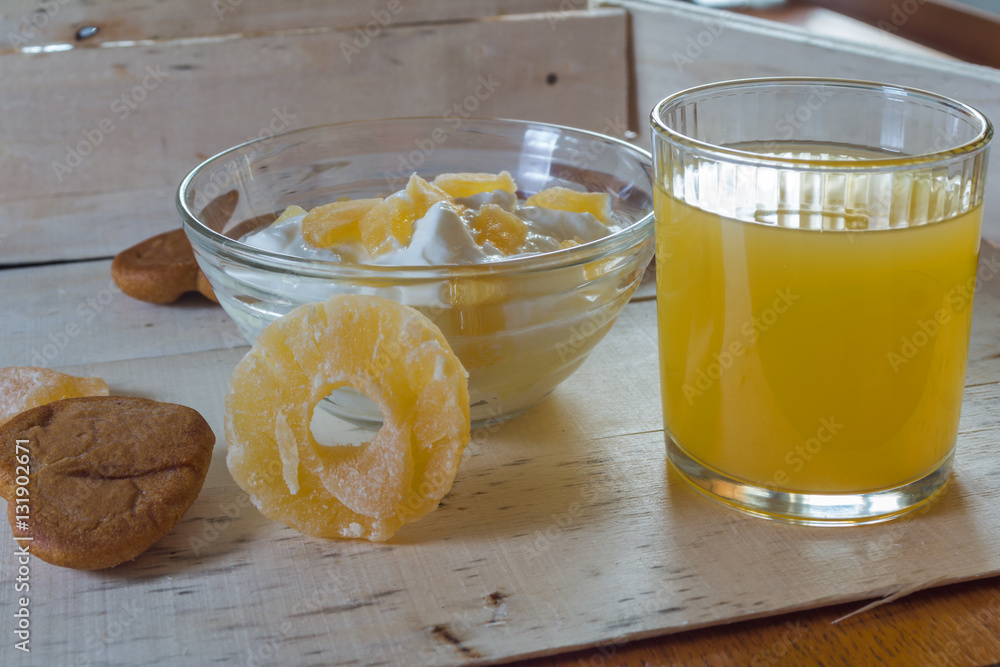 Breakfast with Yogurt with pieces of pineapple and orange juice on a wooden background Breakfast with Yogurt with pieces of pineapple and orange juice on a wooden background