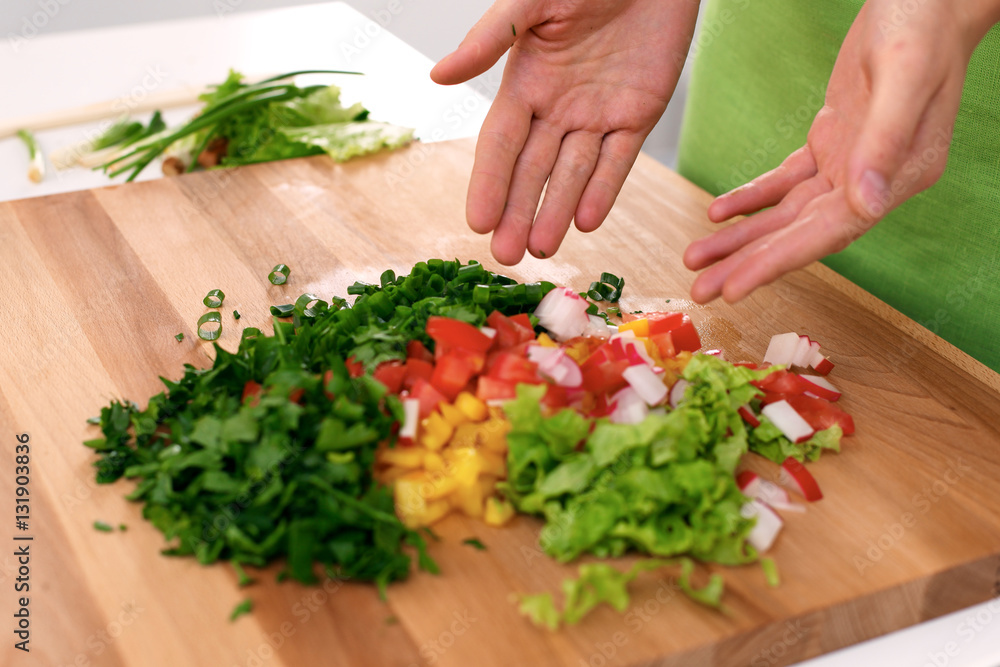 Close up of  woman's hands cooking in the kitchen. Housewife offering ​​fresh salad. Vegetarian and healthily cooking concept