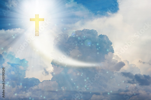 Crucifix or cross on heaven cloudy sky with lens flare