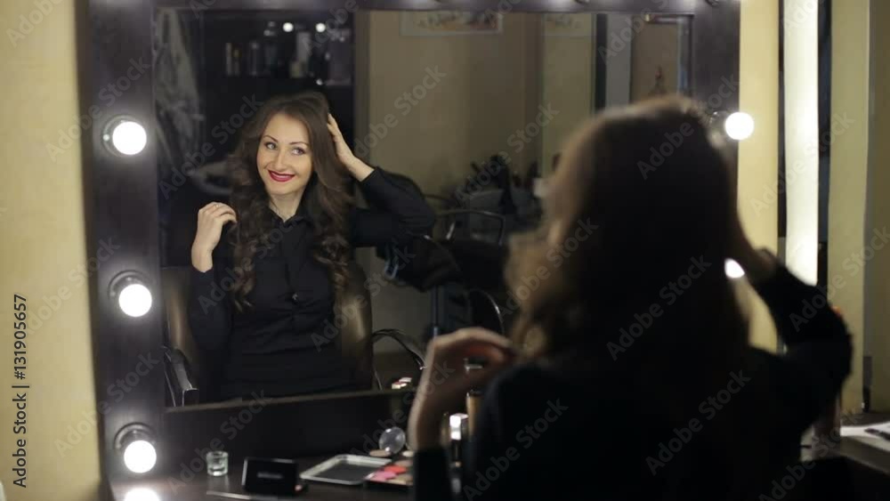 A young girl looks at herself in the mirror at the beauty salon. A young girl looks at herself in the mirror at the beauty salon.