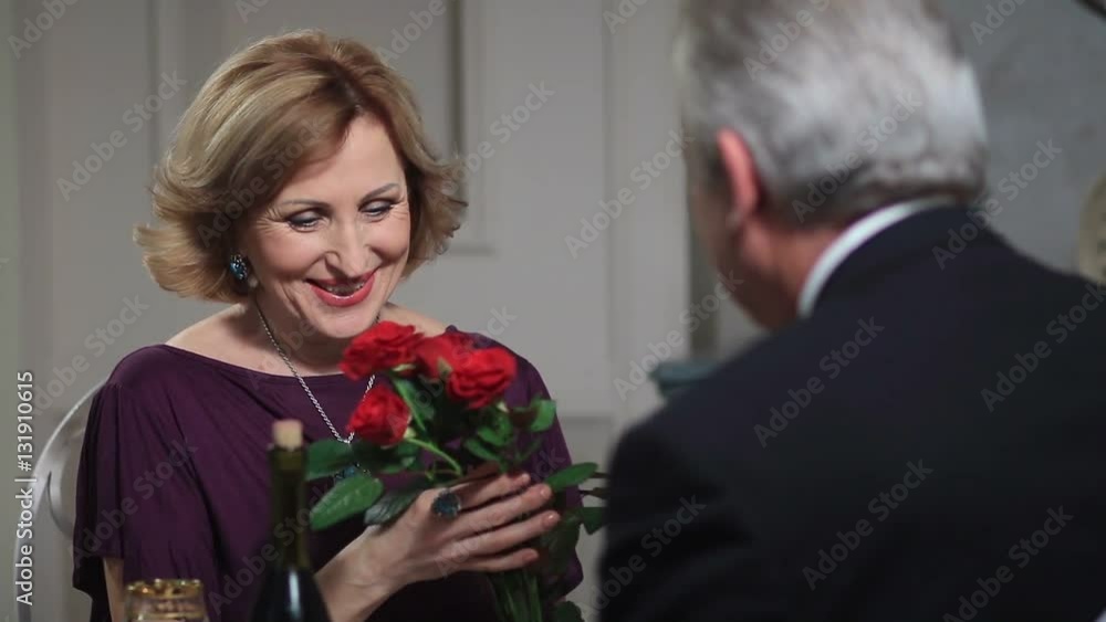 Smiling senior woman receiving flowers from man Smiling senior woman receiving flowers from man