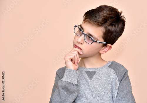 Thoughtful cute young boy with glasses 