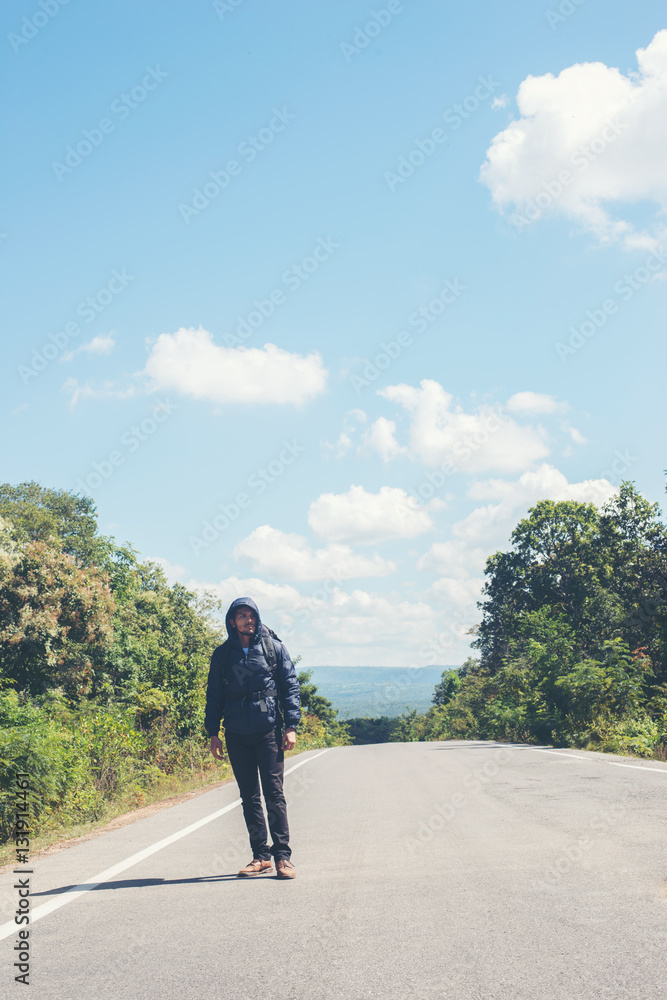 Rear of hiker man walking on the rural road on vacation. Holiday tourism concept.