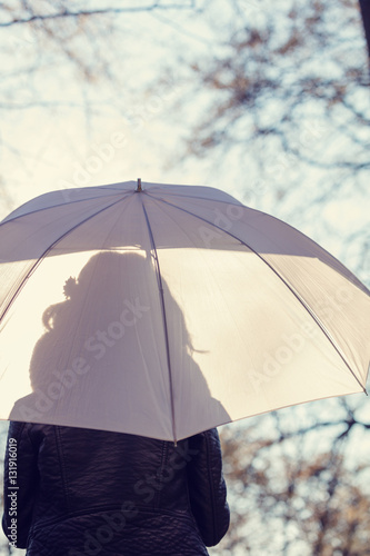 Silhouette of a girl in nature with a white and transparent umbrella.