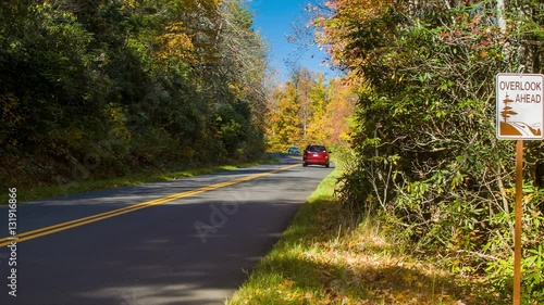 Vehicles Traveling on the Blue Ridge Parkway Past an Overlook sign near Grandfather Mountain, NC on a Sunny day with Fall Colored Leaves photo