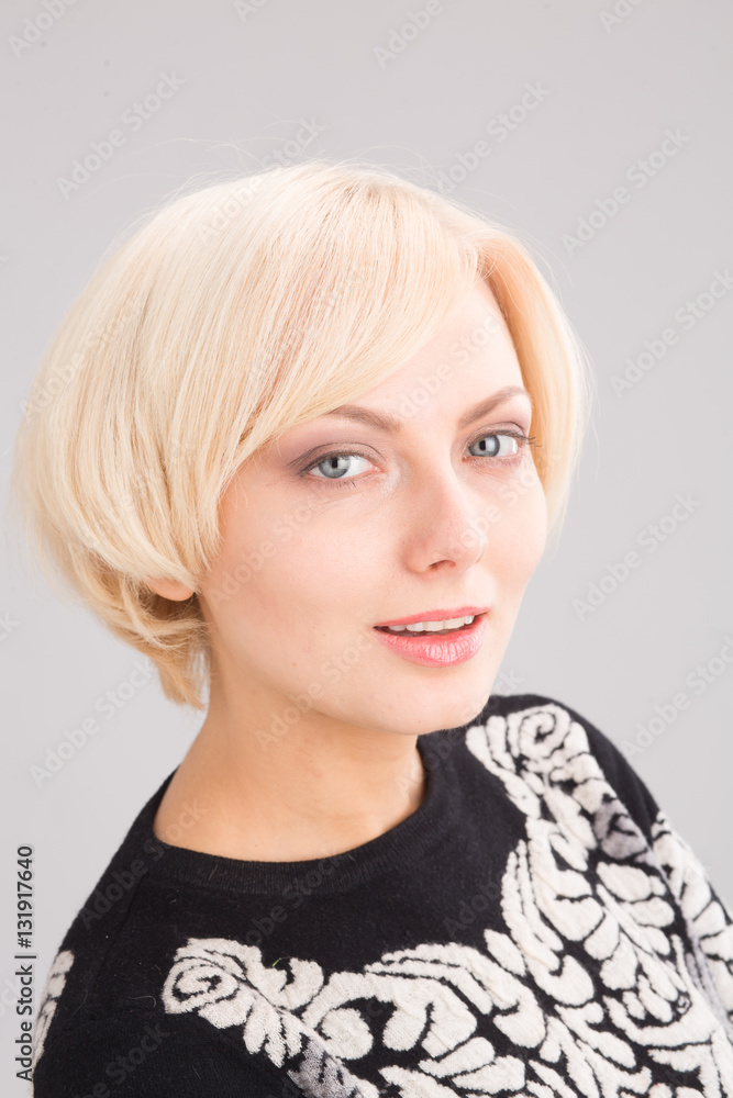 Portrait of beautiful blond lady looking at camera in studio. Blond woman with perfect hait cut isolated on grey background. Portrait of beautiful blond lady looking at camera in studio. Blond woman with perfect hait cut isolated on grey background.