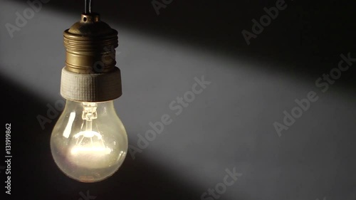 Una vecchia lampada al tungsteno mossa dal vento, si accende in modo intermittente. photo