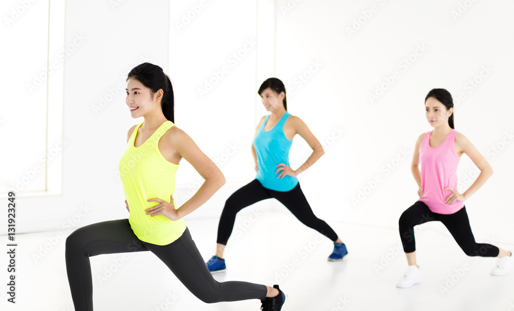 Fototapeta premium smiling young fit group stretching and squat