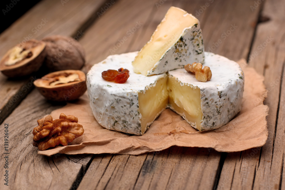 Camembert with nuts,raisins and on rustic wooden background.selective focus
