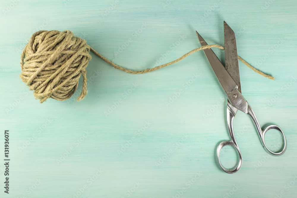 Vintage scissors and roll of twine on teal background