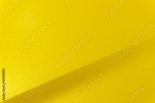 Fragment of yellow steel car bodywork, vehicle silver paint coating texture, selective focus, abstract