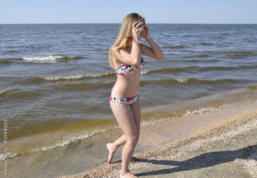Blond girl in a bikini on the beach. Beautiful young woman in a colorful  bikini on sea background Stock Photo | Adobe Stock