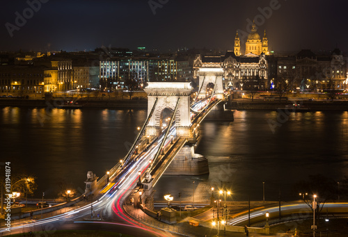 Perspective night view with Chain Bridge, Gresham Palace and Saint Stephen Basilica in Budapest