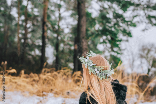 portrait from behind the girl in a wreath of pine with their long blonde hair is the forest. Effect retro photo, grain