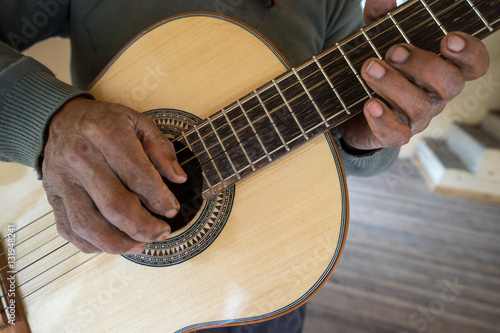 hands of an Ecuadorian luthier holding up a finished classical guitar in San Bartolome