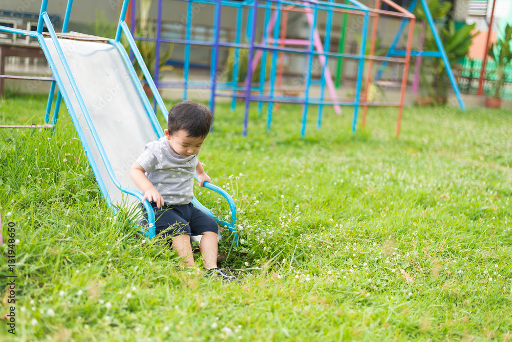 Little Asian kid playing slide at the playground Little Asian kid playing slide at the playground