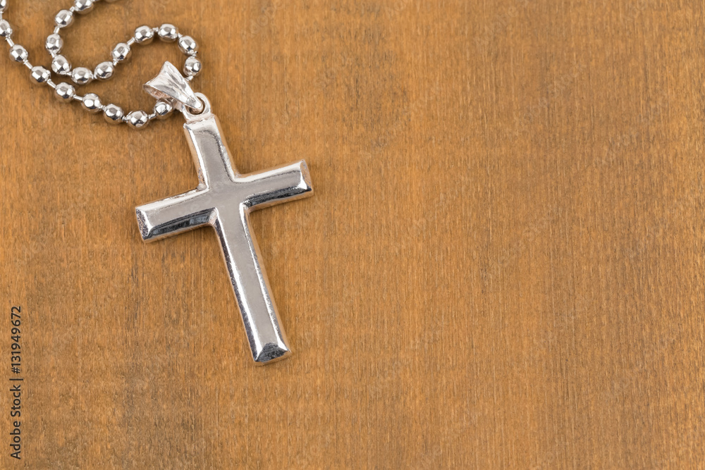 Silver cross with necklace on wooden background