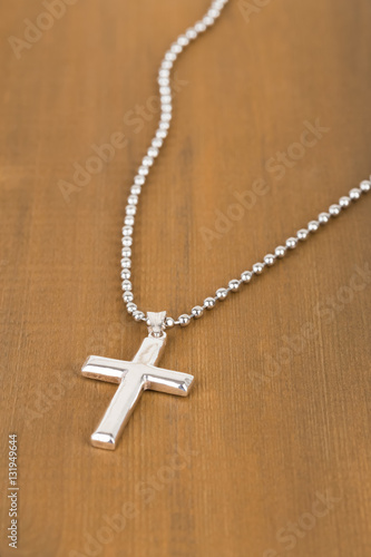 Silver cross with necklace on wooden background