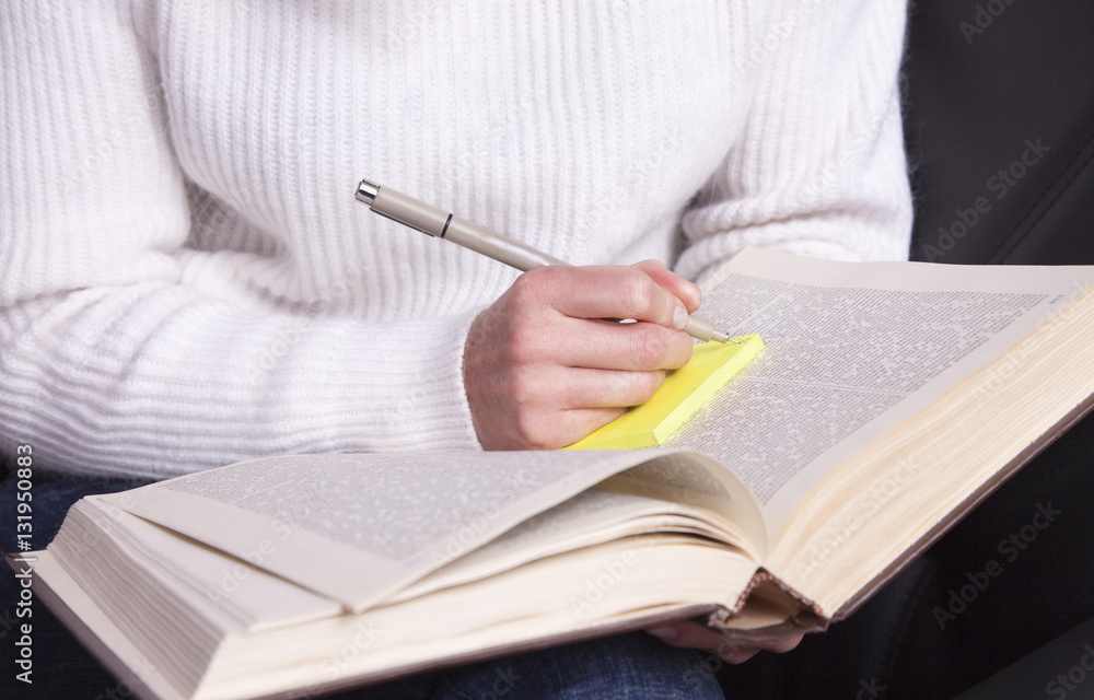 Girl with a book in hand taking notes with a pen. Girl with a book in hand taking notes with a pen.