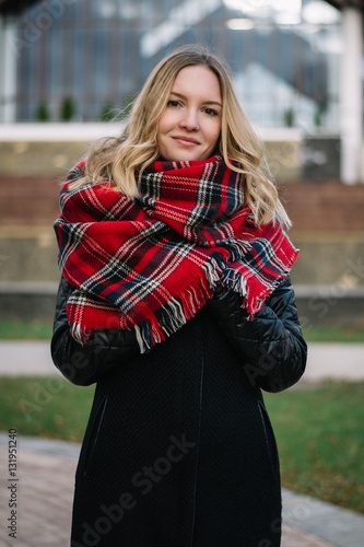 Happy woman with a scarf. Autumn. Autumn portrait of the beautiful girl. Office building. Fashionable portrait of a girl model with waving red scarf. Autumn portrait in the city. © patho1ogy