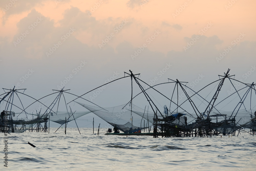 Silhouette of traditional fishing method using a bamboo square dip net with sunrise sky background,livelihoods of fishermen at Pakpra, Phattalung in Thailand