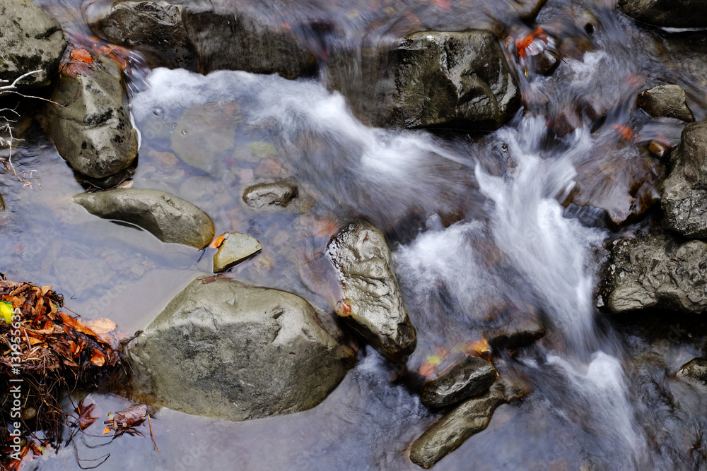Obraz premium Stream flowing through rocky path in mountains