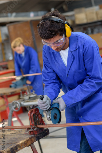 apprentice using circular saw in metallurgy workshop