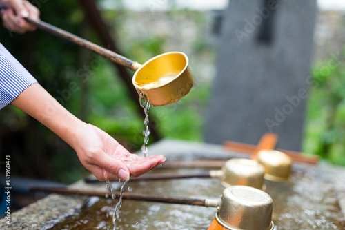 Canvas Print Woman using the water bamboo ladle for purification