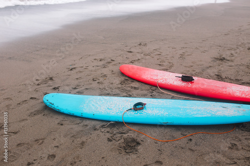 Red and blue surfboards lays on the beach 