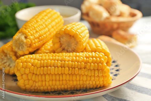 Plate with tasty boiled corncobs on kitchen table, close up view