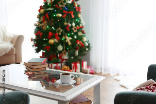 Table with books and cup in living room decorated for Christmas