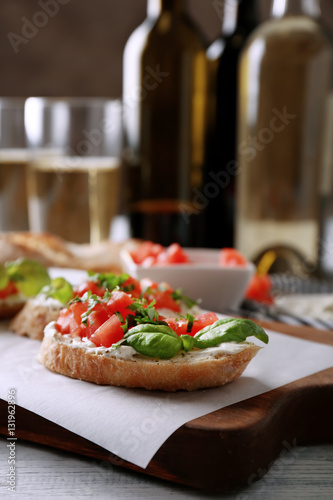 Delicious bruschetta with chopped tomatoes and basil on parchment, closeup