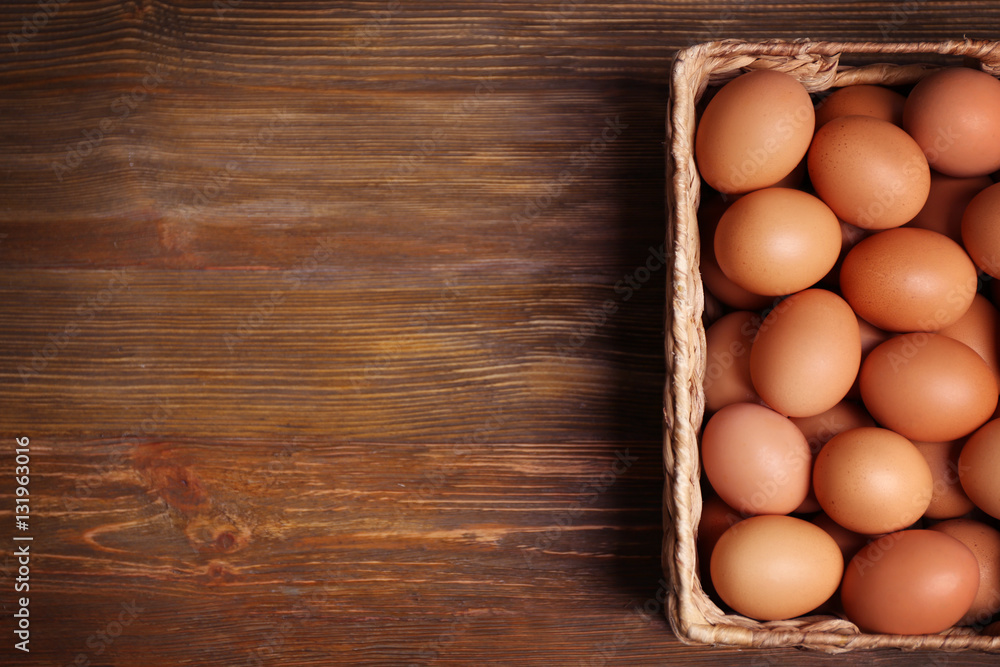 Raw eggs in basket on wooden background Raw eggs in basket on wooden background